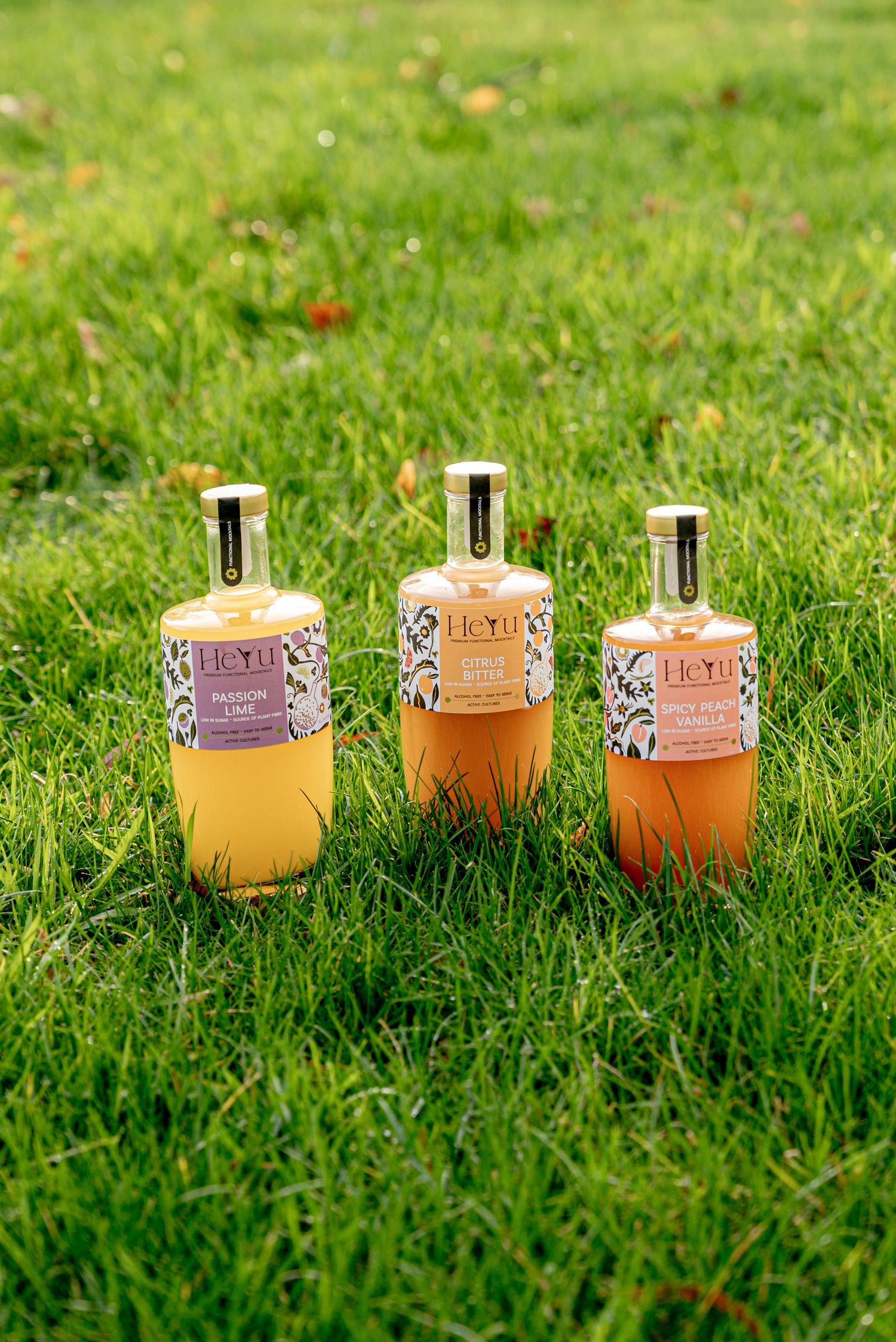 Picture of three Heyu mocktails bottles on a grass field