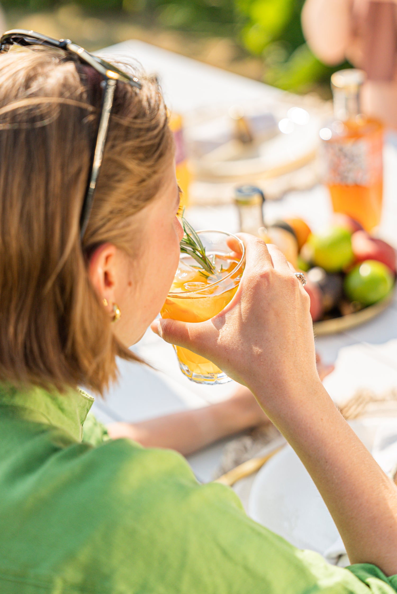 A women in a green dress drinking a Heyu mocktail at a picnic table