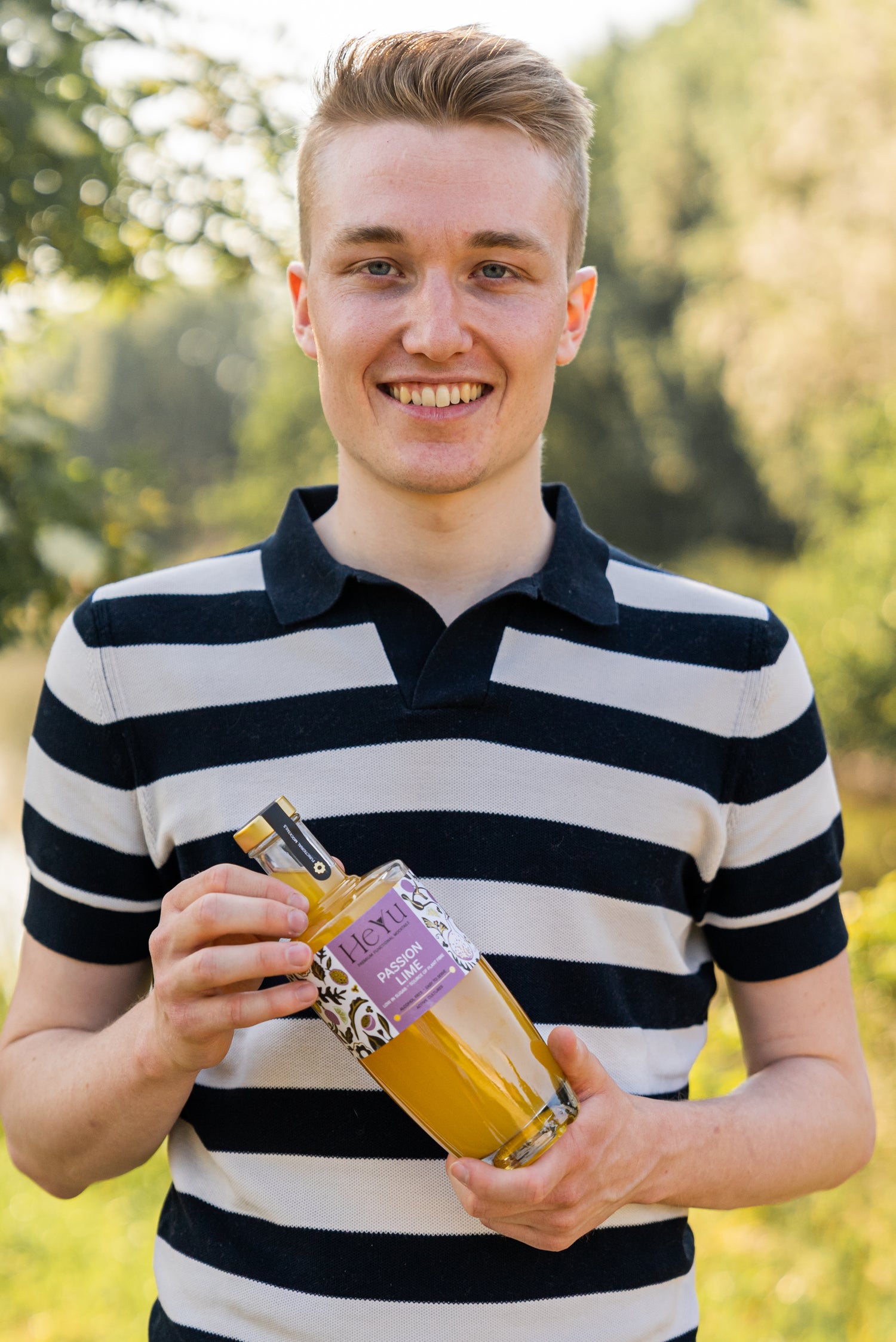 The founder of Heyu holding a bottle of Passion Lime mocktail